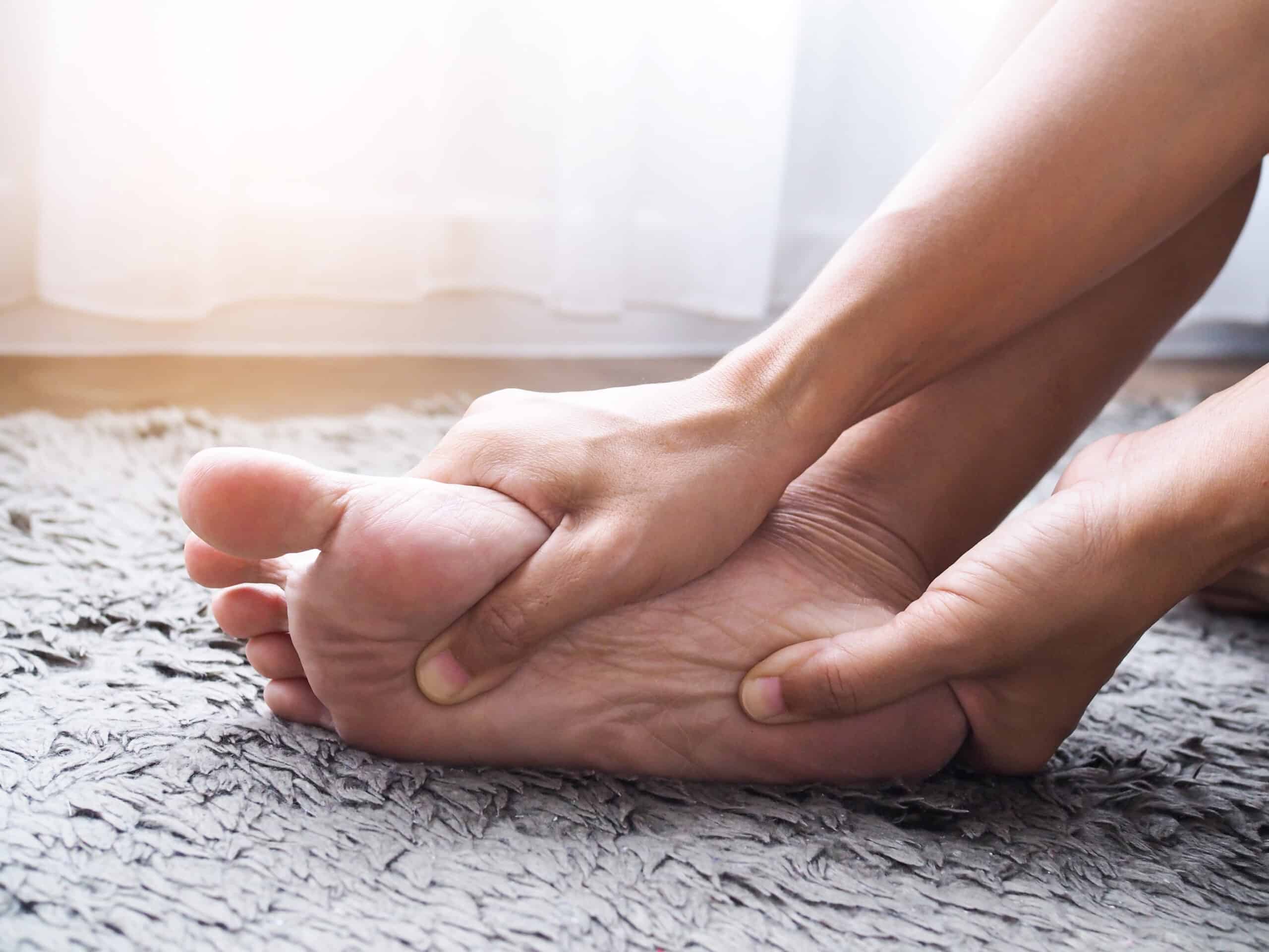 person rubbing the bottom of their foot, because it is in pain.