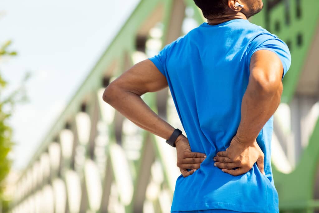Sports injury. Young sportsman suffers from lower back pain while exercising. High quality photo