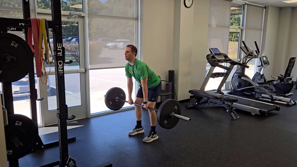 Male Patient deadlifting free-weights in medical facility gym