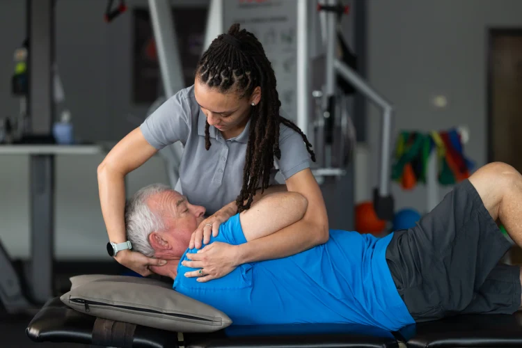 a female physical therapist helping an older patient with a neck stretch as a treatment