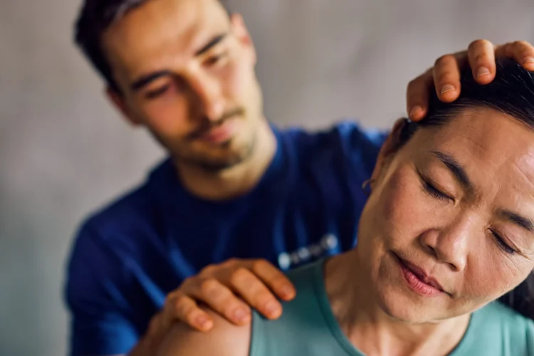 an older asian woman getting her neck examined by a physical therapist