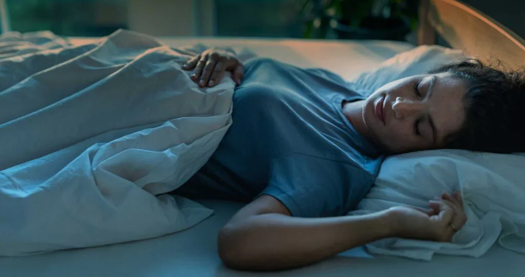 Young pretty woman sleeping in bed in night with street light coming from windows