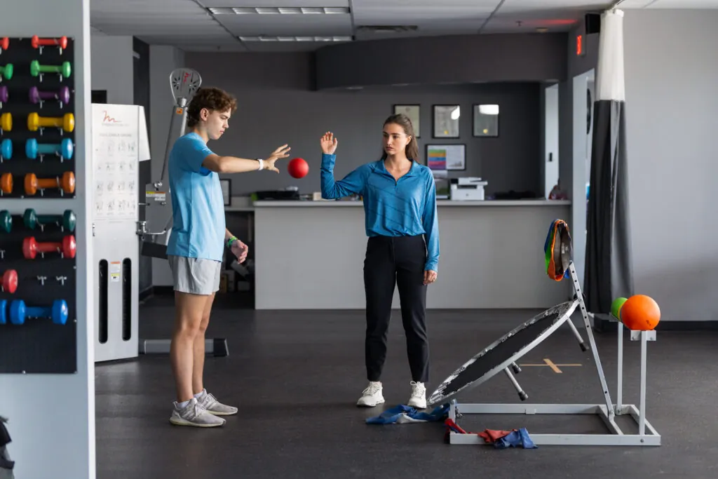 A patient and PT bouncing a ball practicing wrist and grip strength therapy