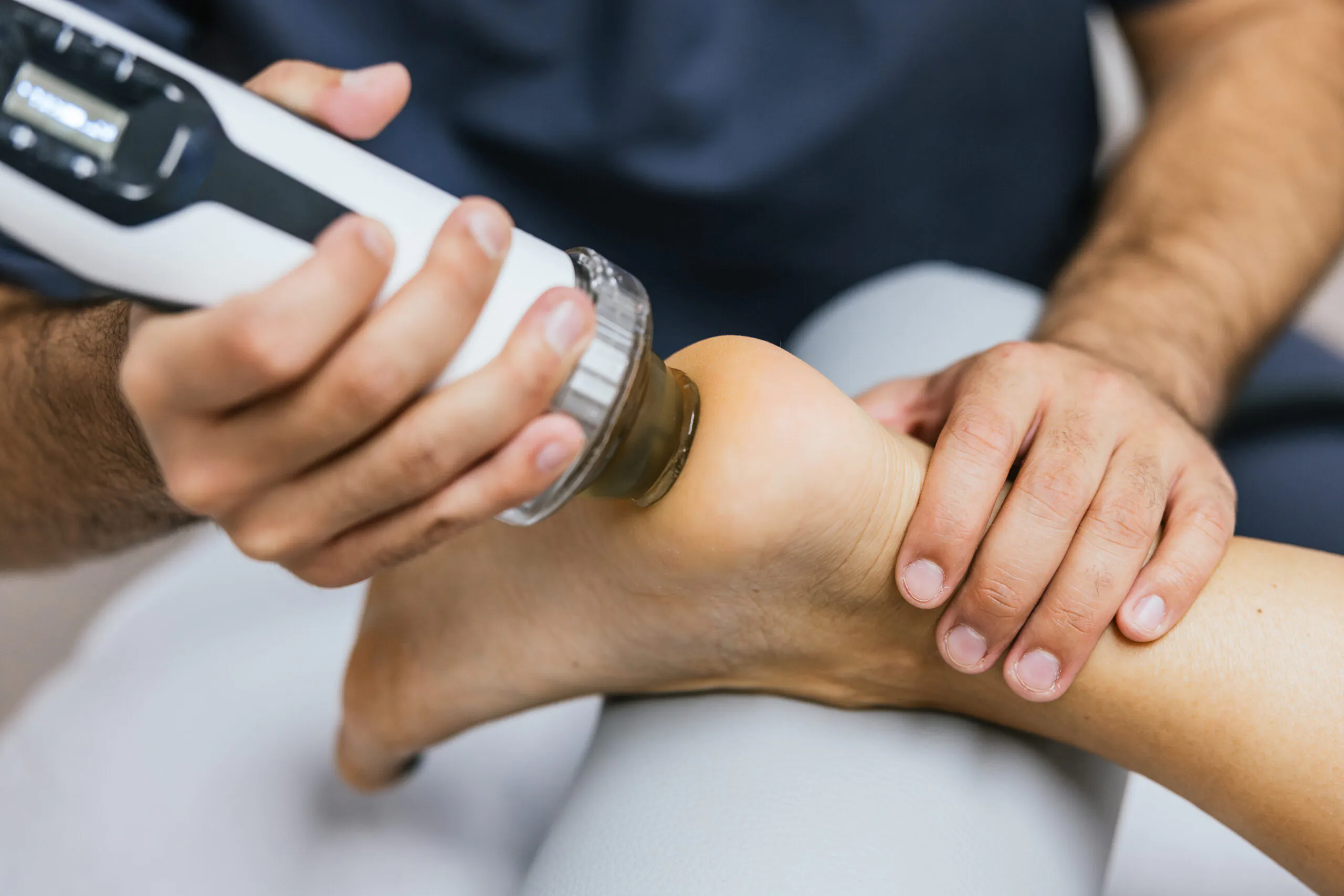 Medical professional applying radial shockwave therapy to a patient's foot heel, treating plantar fasciitis for pain relief and recovery