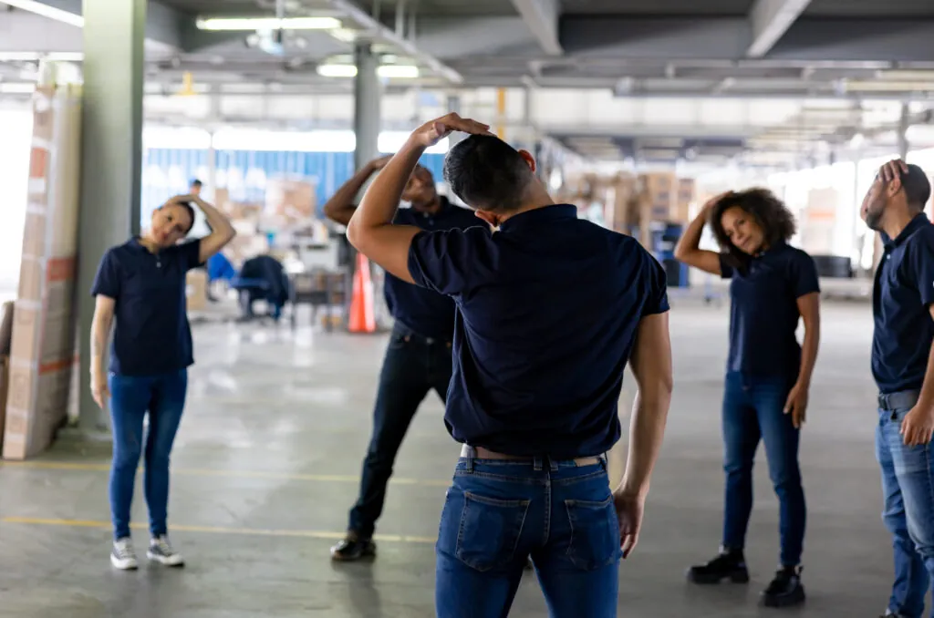 Group of workers stretching on an active pause while working at a warehouse