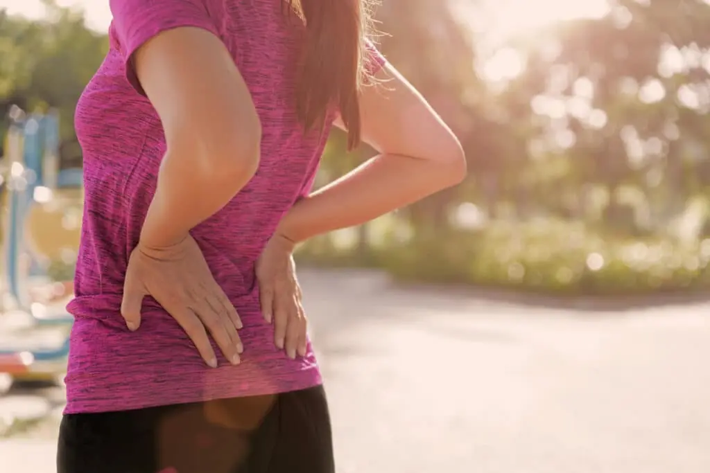 Young asian woman feel pain on her back and hip while exercising, health care concept.