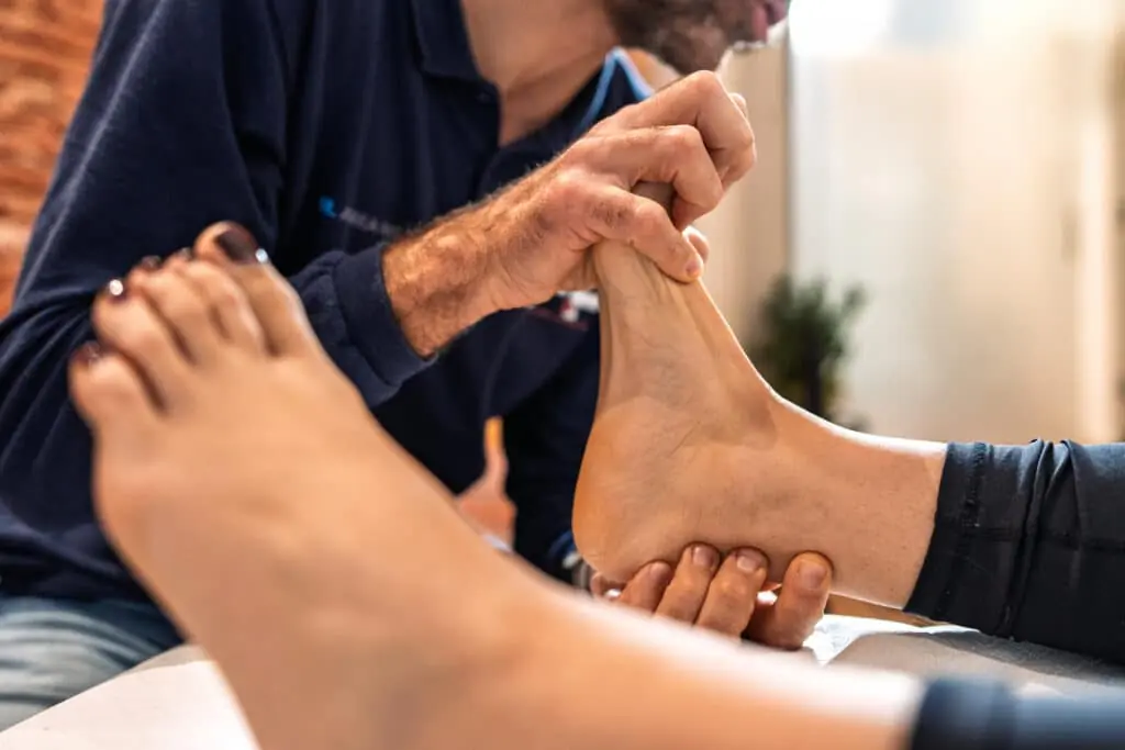 Close-up of osteopathic practitioner's hands manipulating patient's ankle. Professional medical treatment in osteopathy clinic, focusing on manual therapy techniques for foot and ankle.