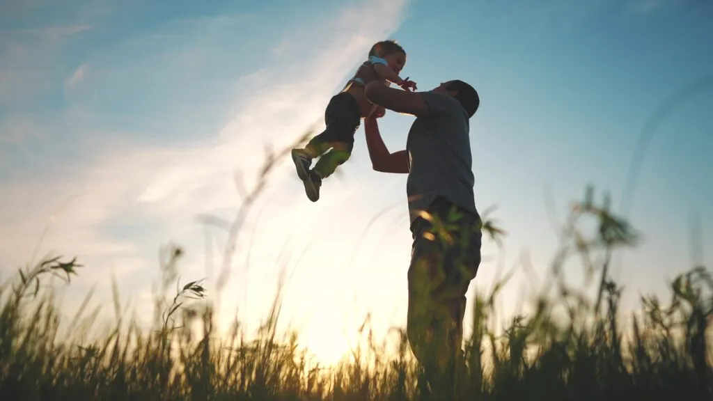 father playing with son in park. happy family kid dream concept. father throws baby up silhouette in summer at sunset. parent and child play toss up silhouette outdoors in the park lifestyle