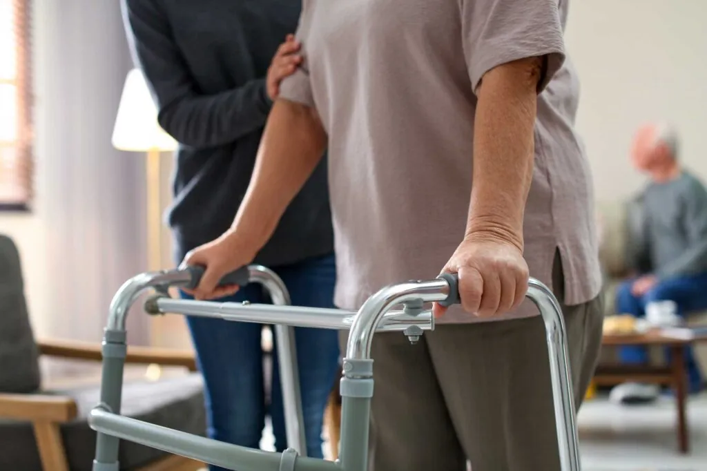 A patient being helped on a walker while recovery after hip replacement.