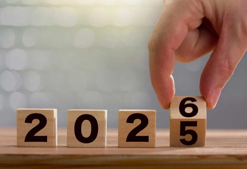 a hand turning a set of block text to 2026 from the previous year 2025