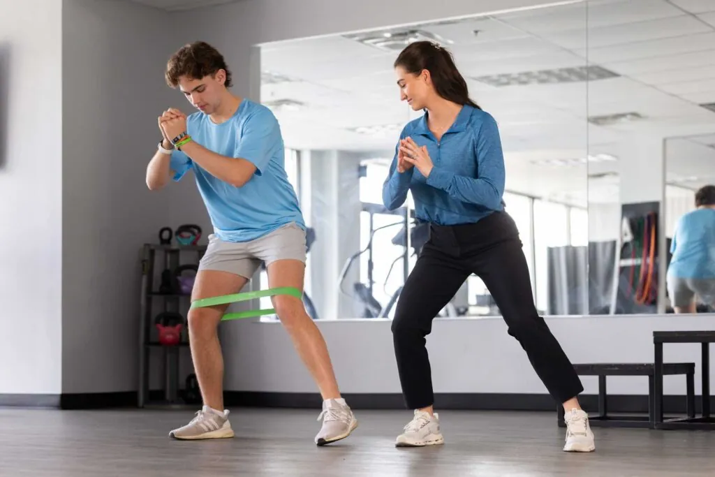 Man and woman doing side-step stretches with exercise band