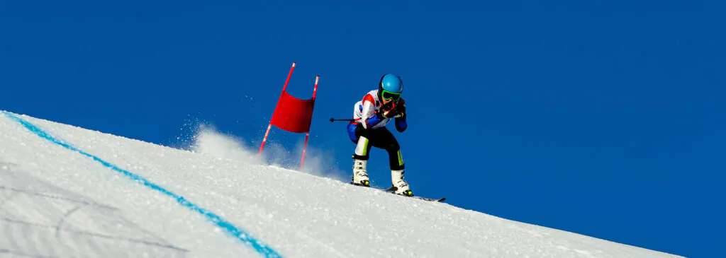 skier passes red gate down snow-covered slope during competitive downhill skiing