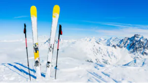 skies and ski poles in the snow on a mountain with a clue sky
