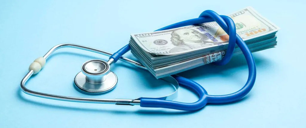 Stack of cash dollars and stethoscope on blue background. The concept of medical strechevka or expensive medicine, doctors salary.