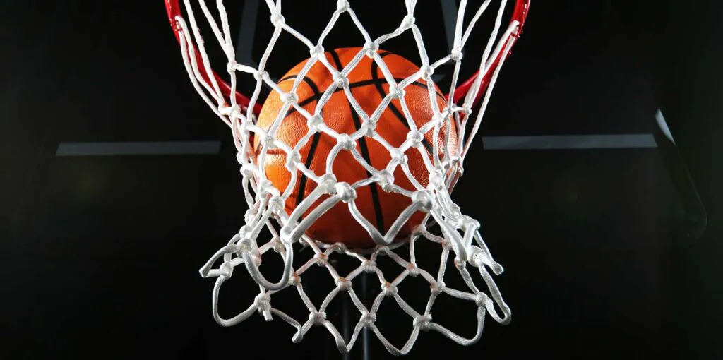 Detail of basketball ball hitting the basket. Isolated on black background.