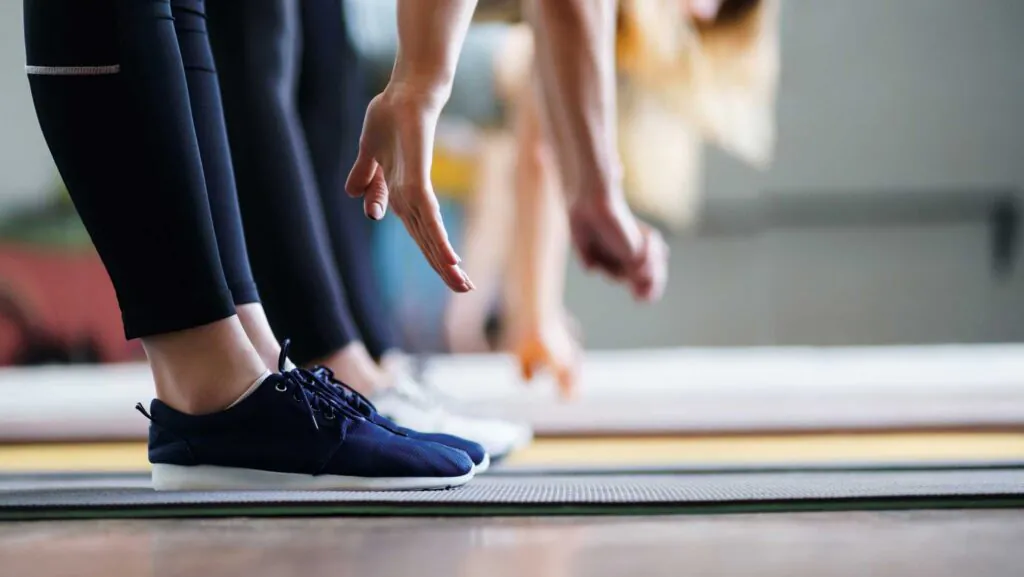 Flexibility, activity, yoga, pilates, warming up concept. Women hands stretching to toecaps on group workout