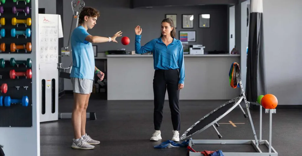male patient having his reflexed evaluated by a bouncing red ball with a PT supervising.
