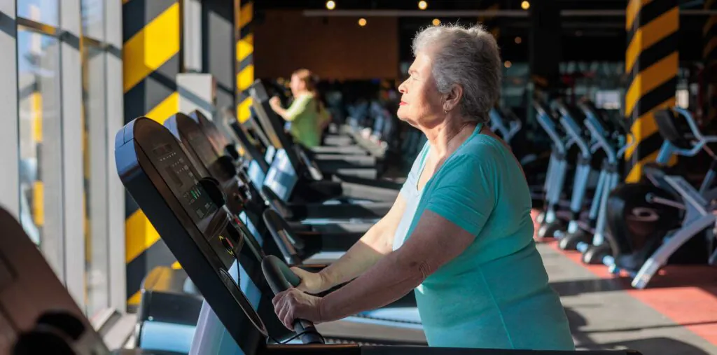 senior woman exercising on treadmill in modern gym. healthy aging, menopause fitness, bone health and osteoporosis prevention. strength, mobility and independence in postmenopausal years 