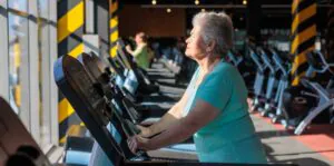 senior woman exercising on treadmill in modern gym. healthy aging, menopause fitness, bone health and osteoporosis prevention. strength, mobility and independence in postmenopausal years