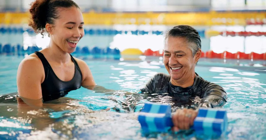 Dumbbell, training and mature woman in swimming pool for exercise, healthy body and strong muscle. Therapist, water and aerobics class for fitness, physiotherapy or rehabilitation of senior person.
