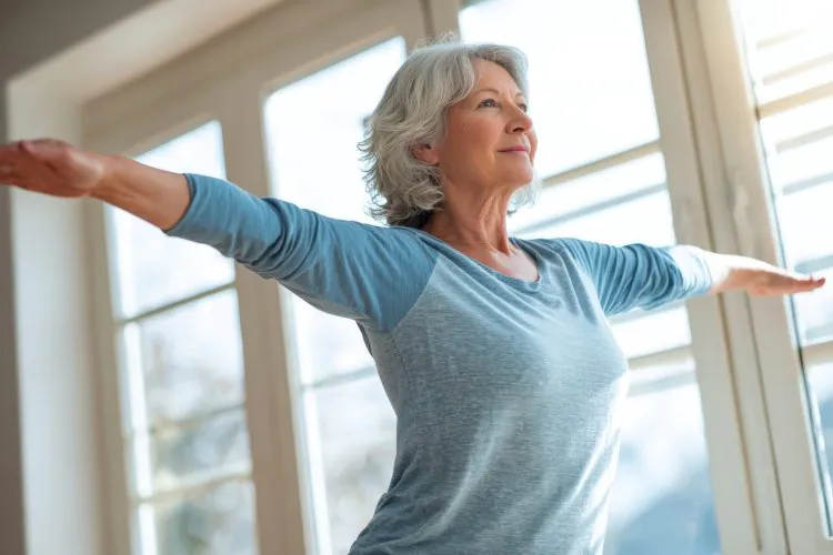 Senior woman doing balance training exercise with simple movements indoors at home, elderly fall prevention and healthy aging concept showing steady focus, physical wellness and medical rehabilitation