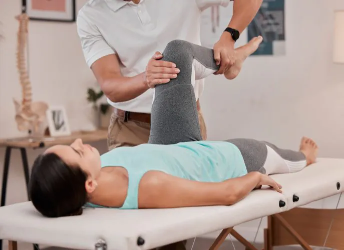 Leg, physiotherapy and healthcare of woman at hospital for rehabilitation, recovery or wellness. Help, physical therapy or female patient with chiropractor for stretching, knee pain or injury healing.